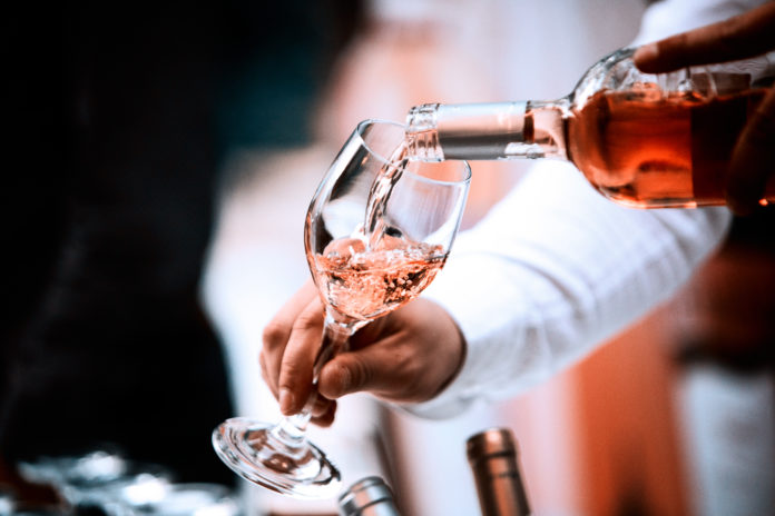waiter pouring a glass of rosé in a wine glass