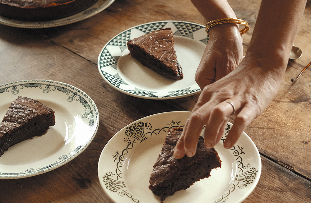 Person putting a slice of chocolate cake on a plate