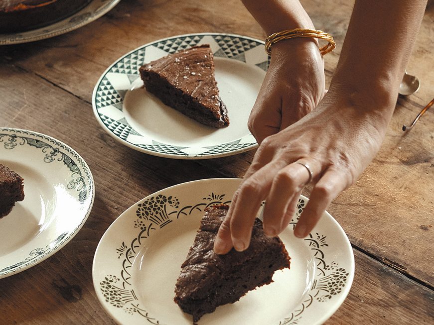 Person putting a slice of chocolate cake on a plate